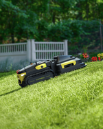 Black and yellow robotic lawn mower by Yarbo on green grass, side view with track wheels and control panel, garden background